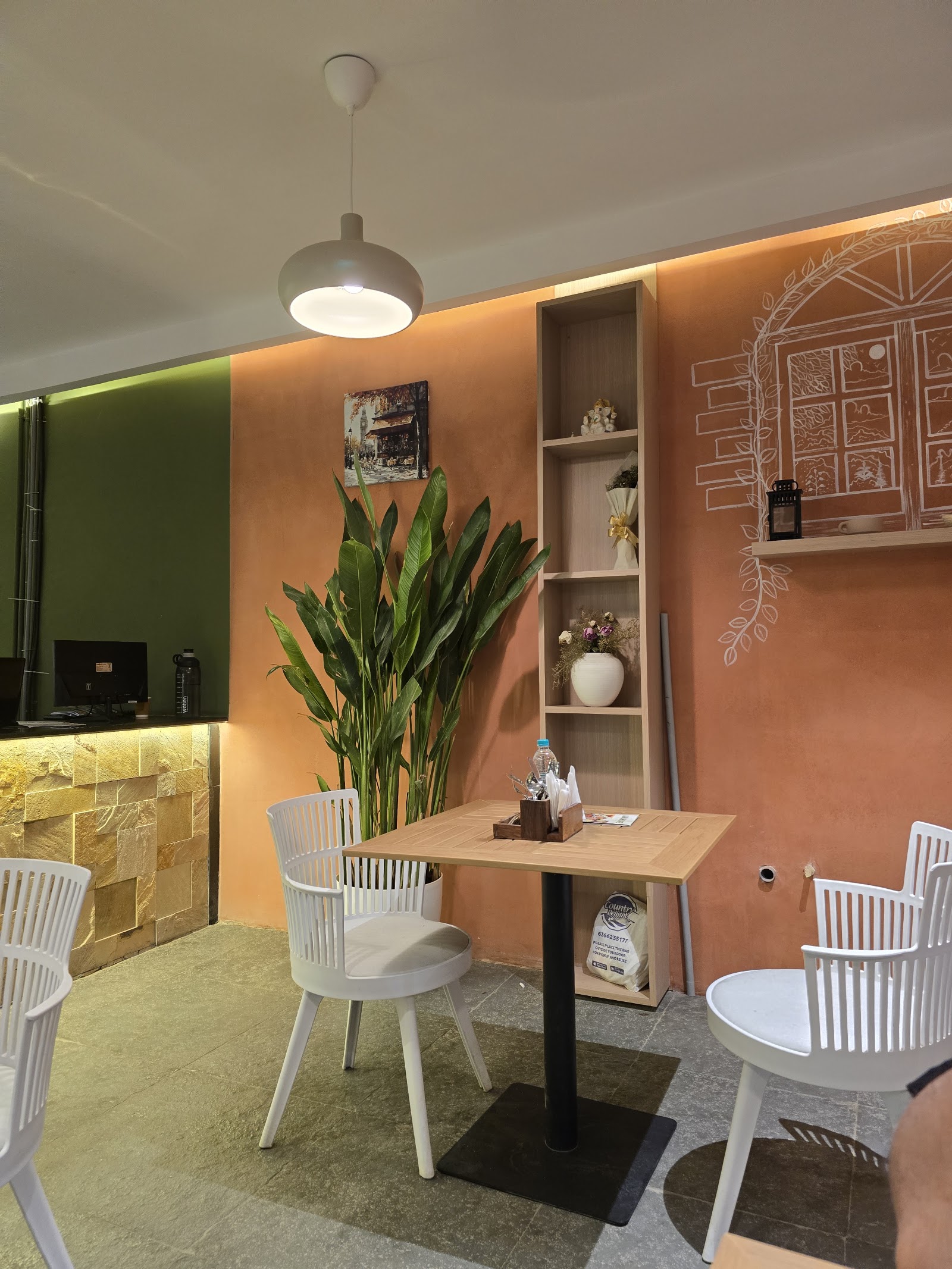 Inside Araah: terracotta walls with a chalk-drawn window mural, an olive green counter wall, white slatted chairs and pale wood tables