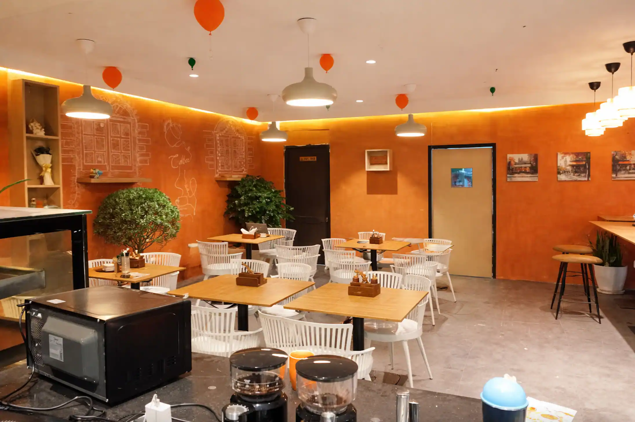 The main room at Araah, looking across wooden tables and white chairs to the counter, under warm cove lighting